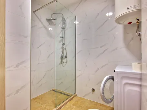 Bathroom with a walk-in shower and washing machine. - image 14