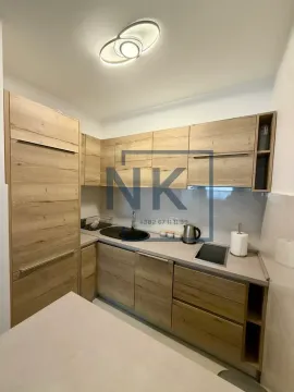 Small kitchen with wooden cabinetry and built-in appliances. - image 2