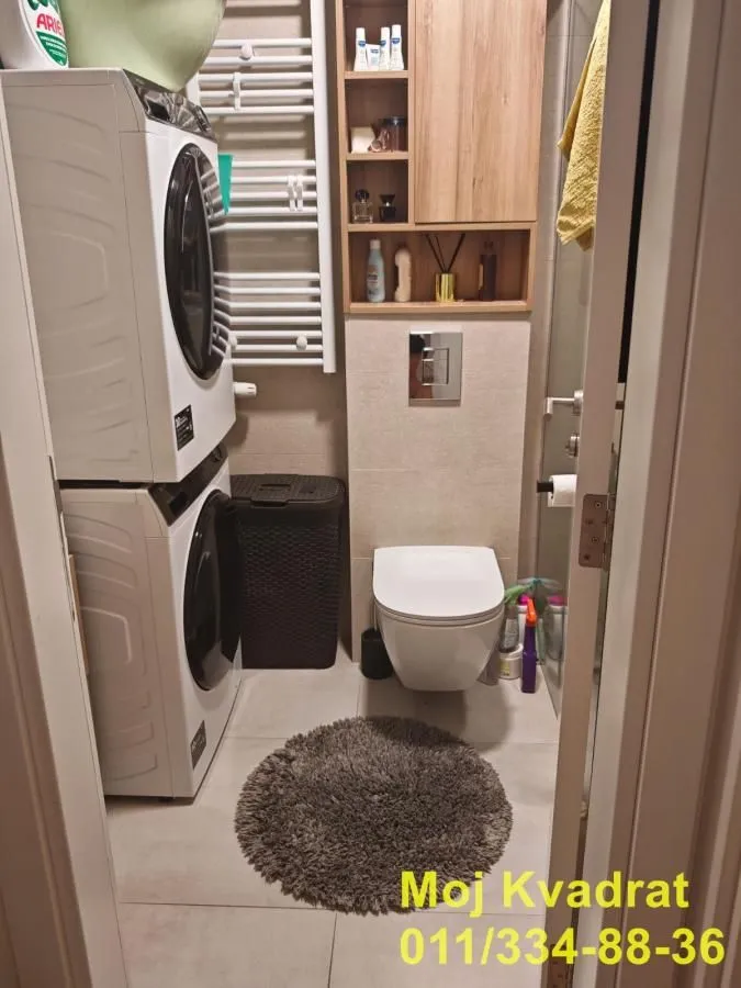 Kompaktno kupatilo sa WC šoljom, ugradnim elementima i mašinama za pranje i sušenje veša.