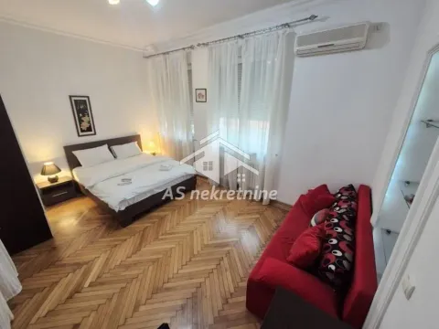 Bedroom with a double bed, parquet flooring, and a red sofa. - image 11