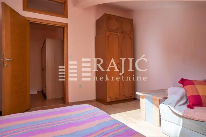 Furnished bedroom with a bed, wardrobe, and table.