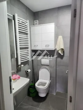 Manje kupatilo sa sivim pločicama, wc šoljom, lavaboom i belim ormarićem. - image 6