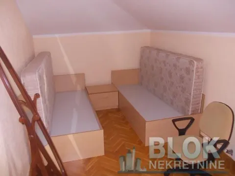 Attic room furnished with two beds and a desk. - image 11