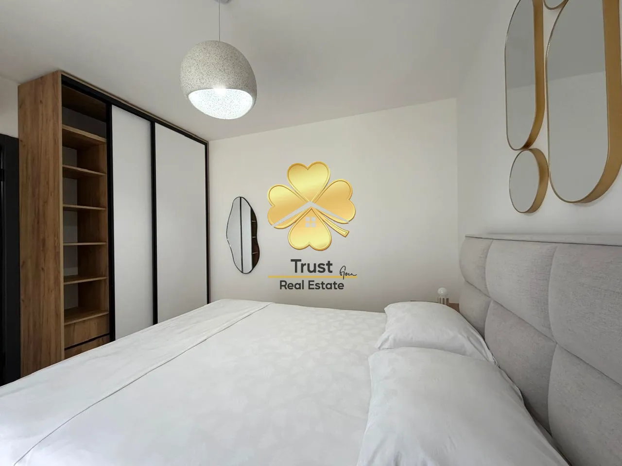 Modern bedroom with a double bed, wardrobe, and decorative mirrors.