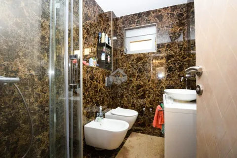 Bathroom lined with marble tiles featuring a shower cabin, washbasin, and sanitary fixtures. - image 13