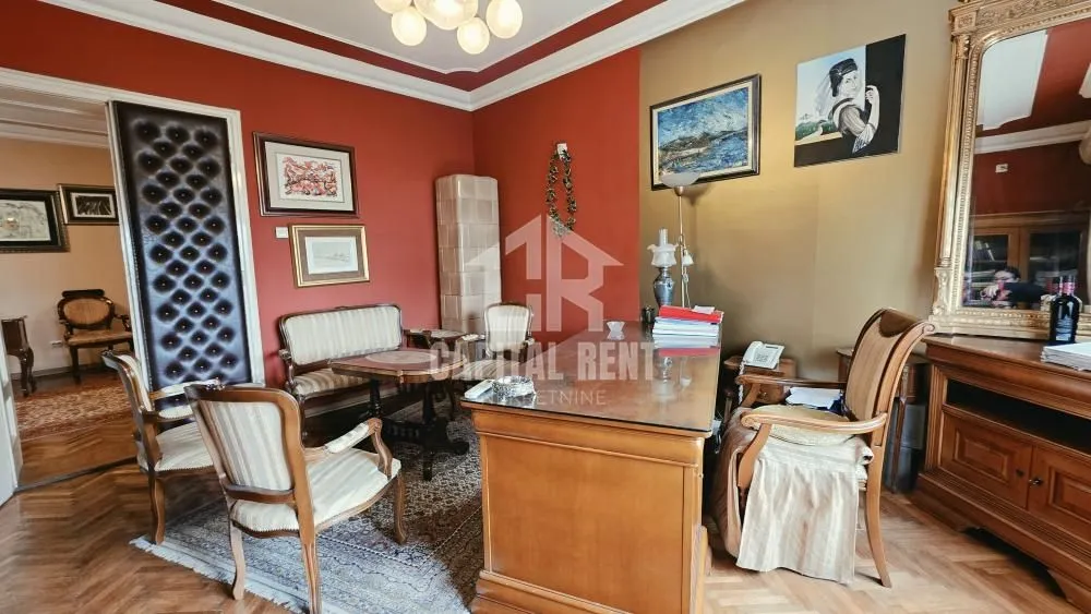 Dnevna soba sa radnim stolom i klasičnim nameštajem.