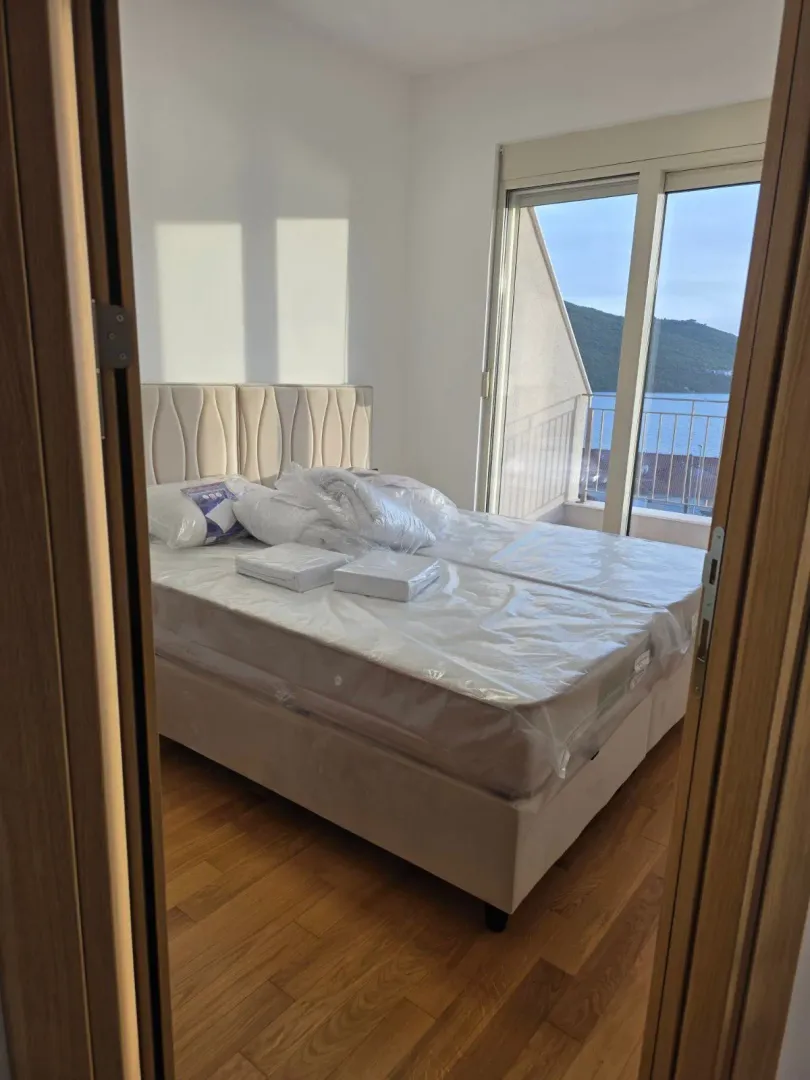 Pogled iz hodnika na spavaću sobu sa krevetom i izlazom na terasu sa pogledom na more.
