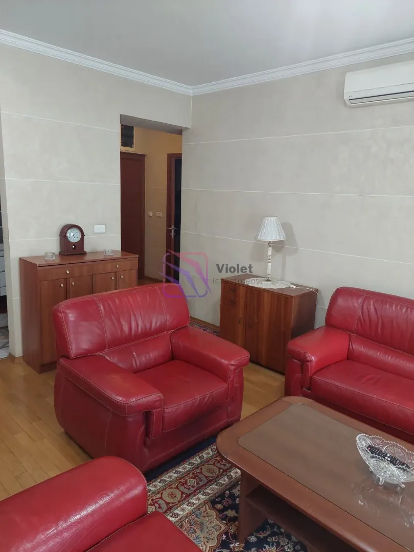 Living room with red leather sofas and wooden furniture.