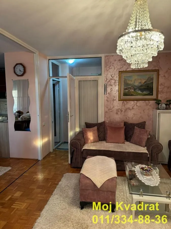 Dnevna soba sa garniturom, stočićem i lusterom.