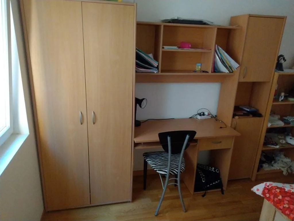 Children's room with a desk, wardrobe, and shelves.