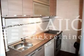 Small kitchen with wooden cabinetry and a sink. - image 5