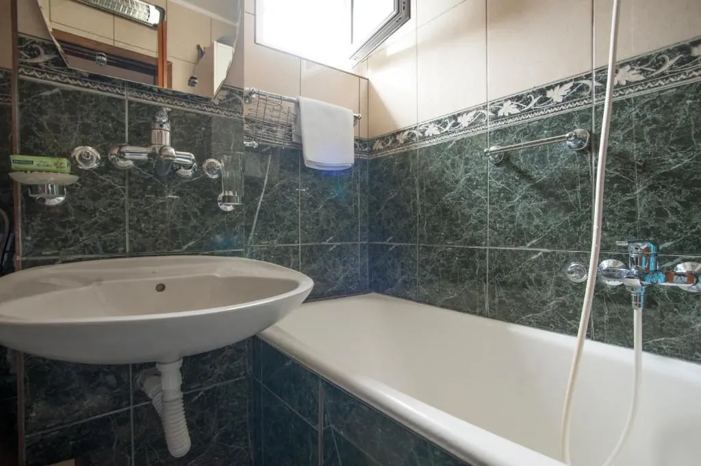 Small bathroom with a bathtub, washbasin and green ceramic tiles.
