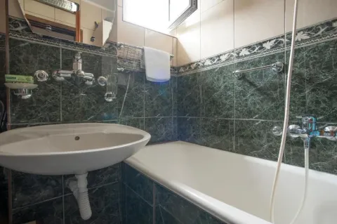 Small bathroom with a bathtub, washbasin and green ceramic tiles. - image 18