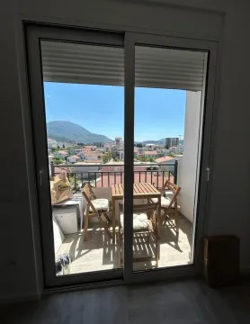 Balcony with a wooden table and chairs and a city view. - image 7
