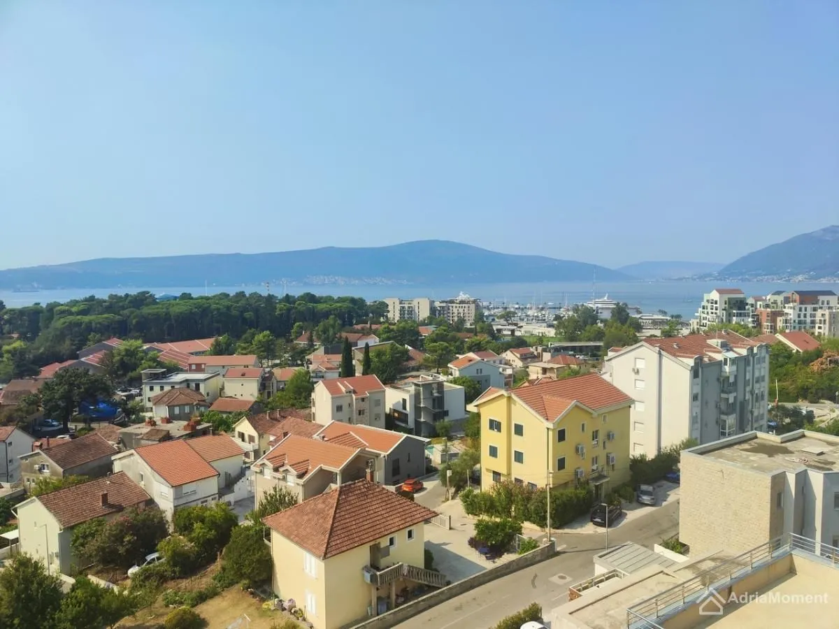 Pogled iz visine na gradsko naselje, more i brda u daljini.