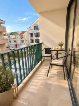 Furnished balcony with a table, chairs, and a view of surrounding buildings. - image 6