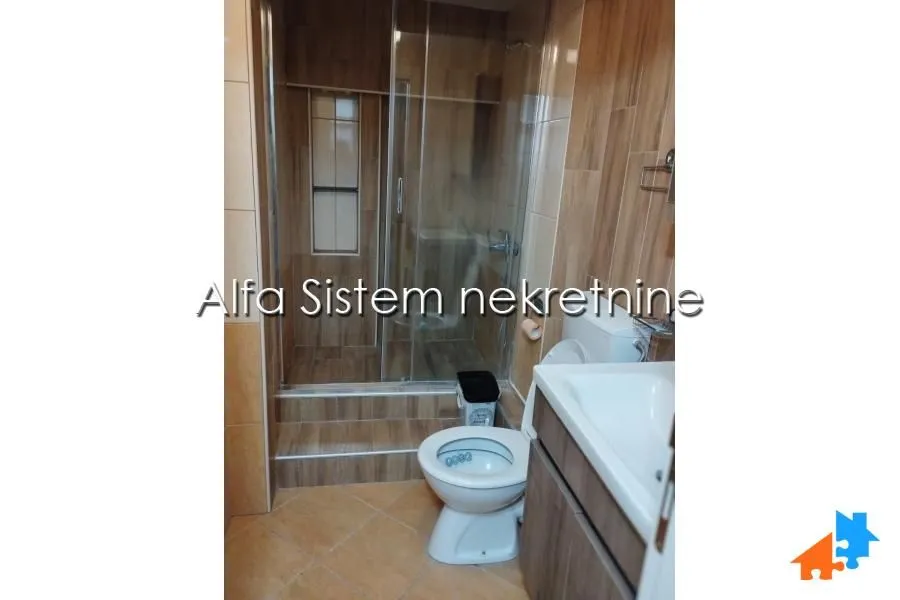 Bathroom with a shower cabin, washbasin, and toilet, finished with wood-pattern ceramic tiles.