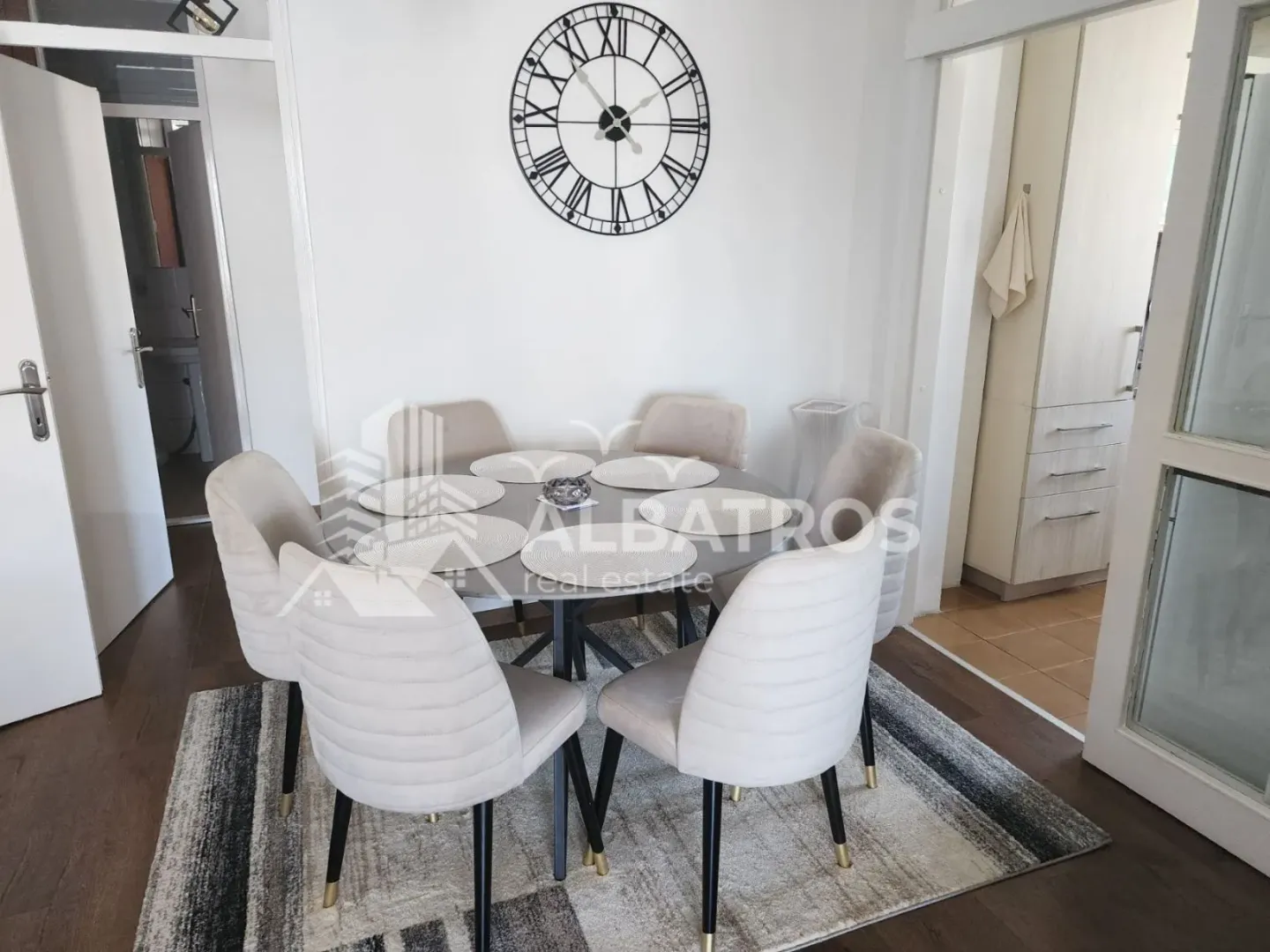 Trpezarija sa okruglim stolom i modernim stolicama.