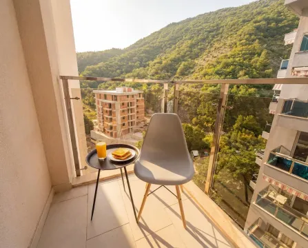 Small furnished balcony with a small table and a view of nature and surrounding buildings. - image 2