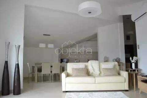 Living room with a sofa and a dining area in the background. - image 9