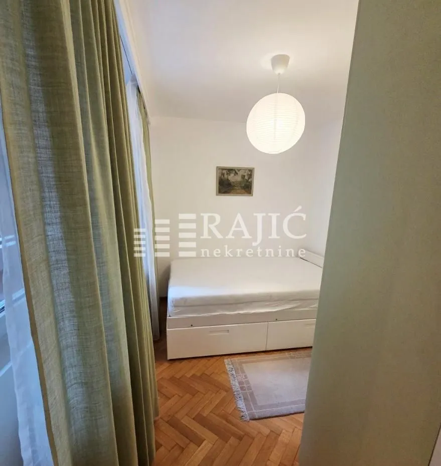 Furnished bedroom with a double bed and parquet flooring.