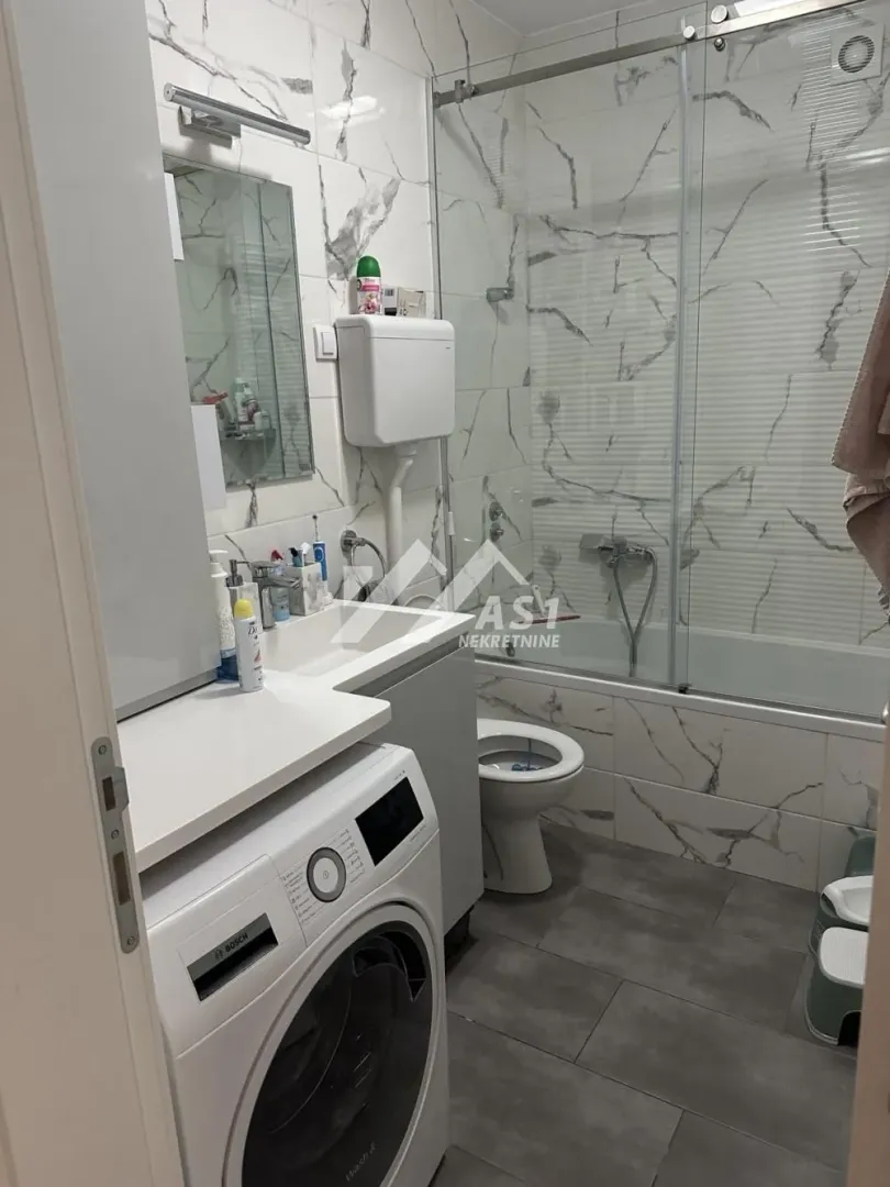 Manje kupatilo sa kadom, umivaonikom i veš mašinom.