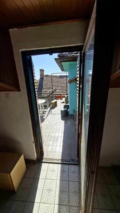 Pogled kroz otvorena vrata na terasu sa pločicama i pogledom na okolne krovove.