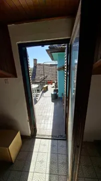 Pogled kroz otvorena vrata na terasu sa pločicama i pogledom na okolne krovove. - image 4