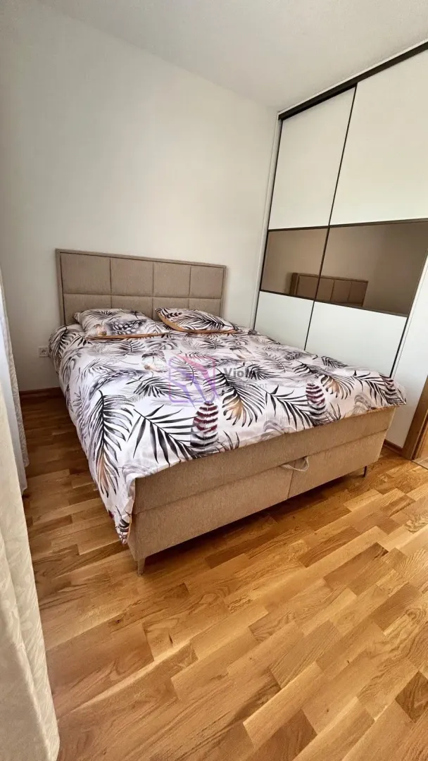 Namještena spavaća soba sa bračnim krevetom i ugradnim plakarom.