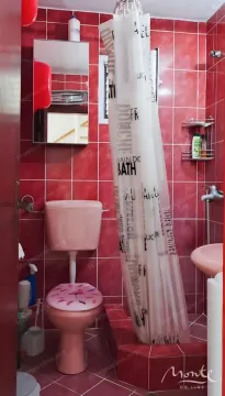 Kupatilo sa crvenim pločicama, wc šoljom, umivaonikom i tuš kabinom sa zavjesom. - image 19