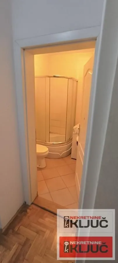 Pogled iz hodnika na kupatilo sa tuš kabinom.