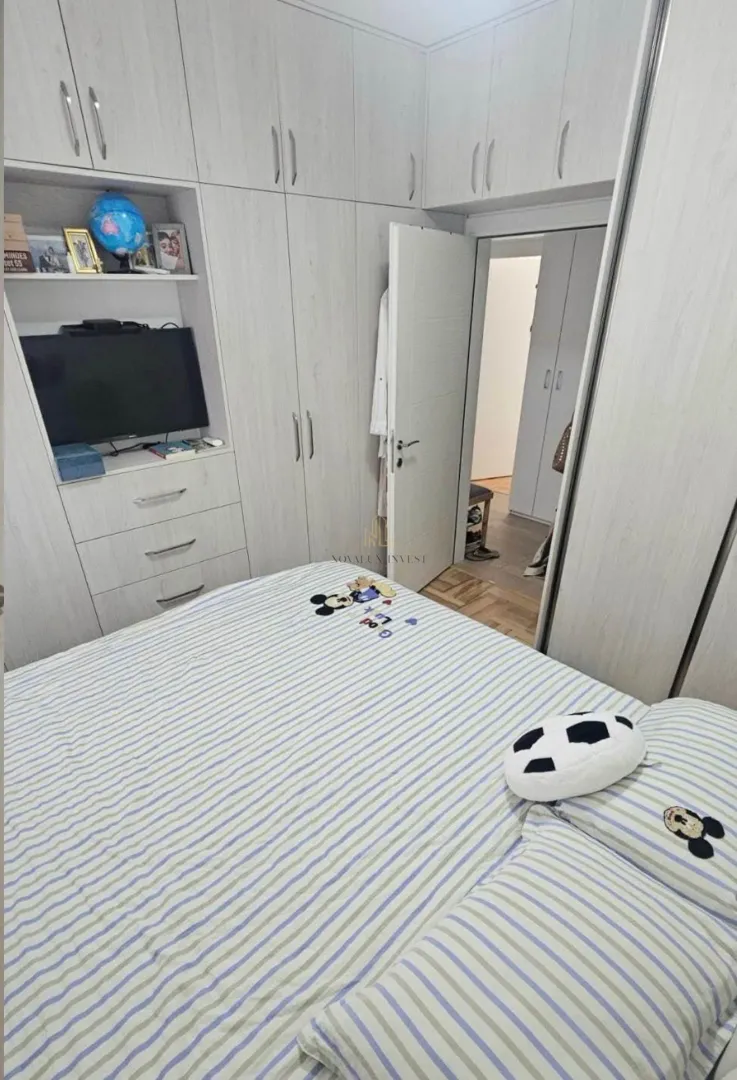 Spavaća soba sa bračnim krevetom, ugradnim plakarima i televizorom.