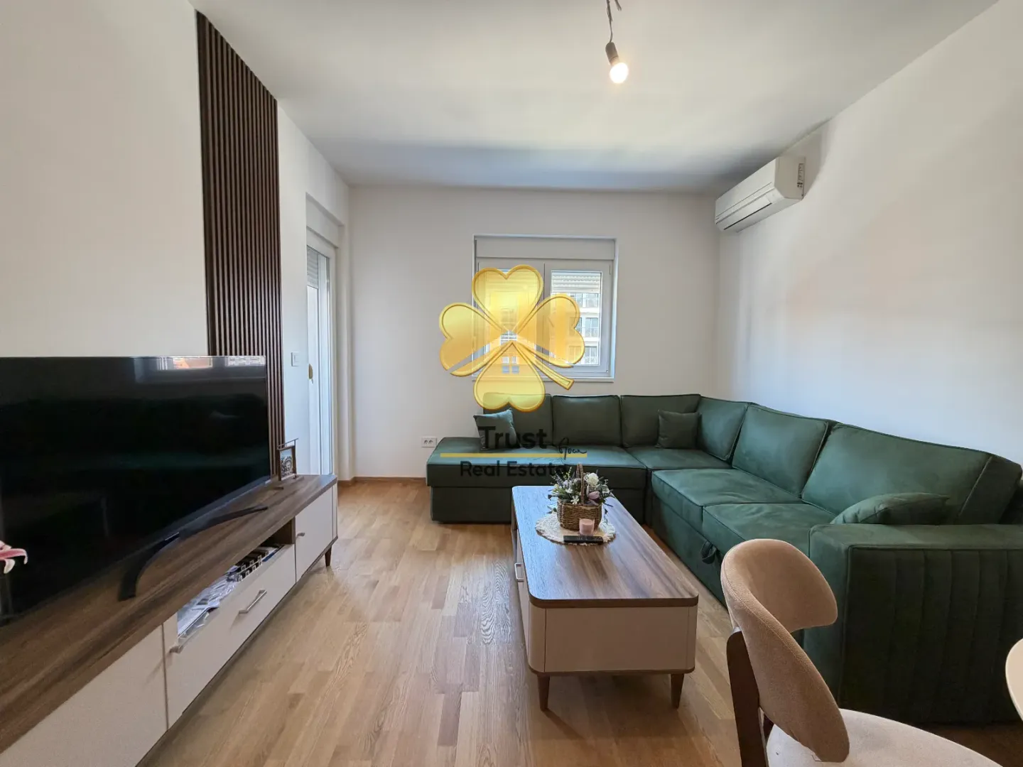 Living room with a sofa set, TV unit, and wooden wall paneling.