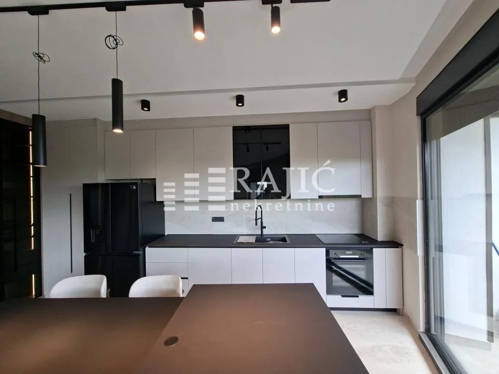 Modern kitchen with white cabinets and black countertops.
