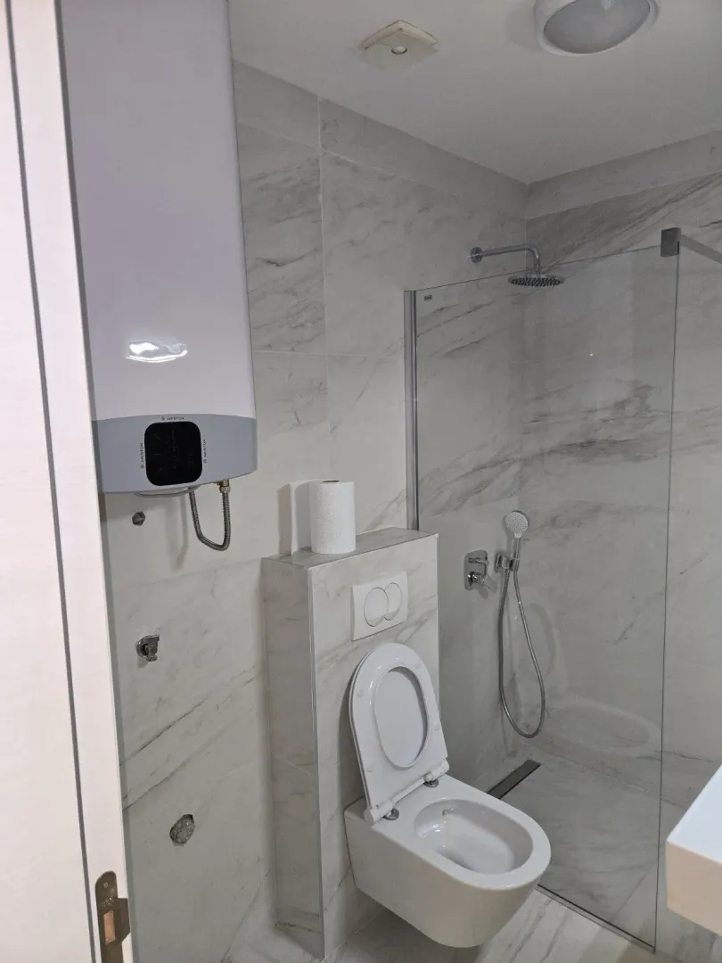 Bright bathroom with a shower cabin and toilet.