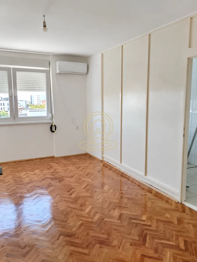Prazna soba sa parketom na podu i ugrađenim plakarom.