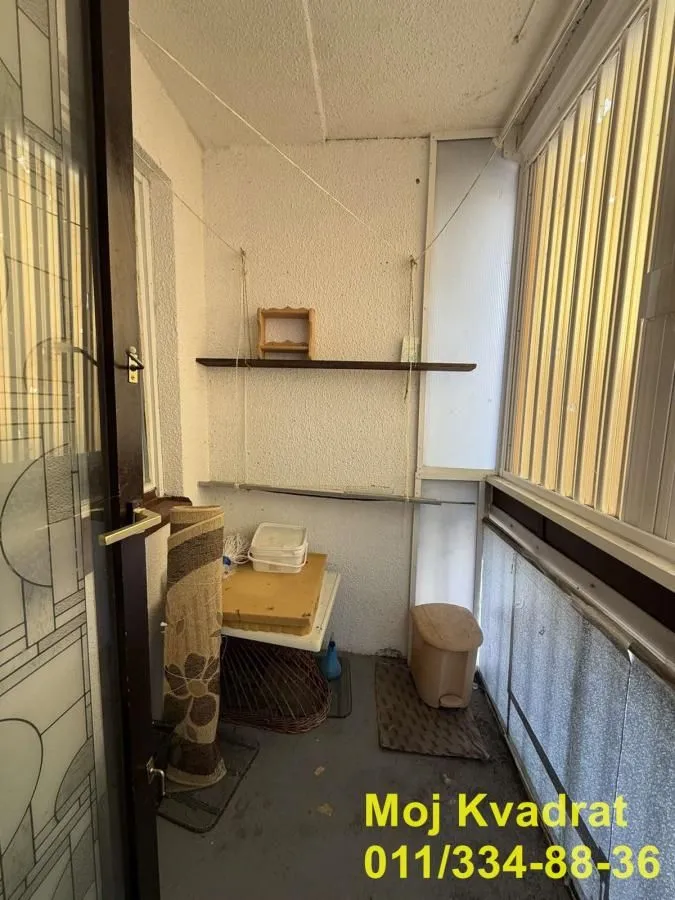 Zastakljeni balkon sa policom i kućnim potrepštinama.