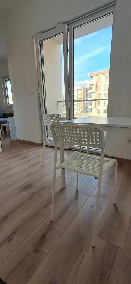 Dnevna soba sa trpezarijskim stolom, bijelim stolicama i pogledom na terasu.