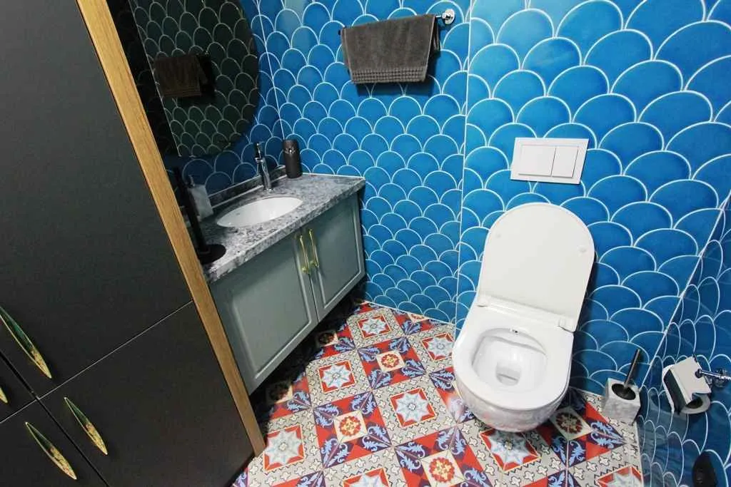 Modern bathroom with a sink, toilet, and blue tiles.