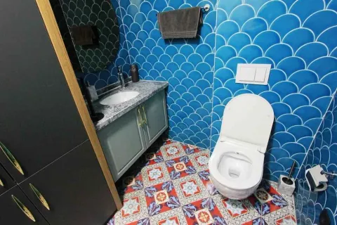 Modern bathroom with a sink, toilet, and blue tiles. - image 6