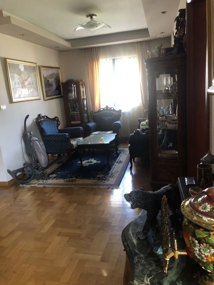 A living room with classic furniture, a rug, and parquet flooring.