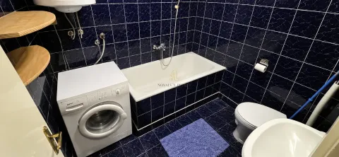 Kupatilo obloženo tamnim pločicama sa kadom, veš mašinom i sanitarijama. - image 8