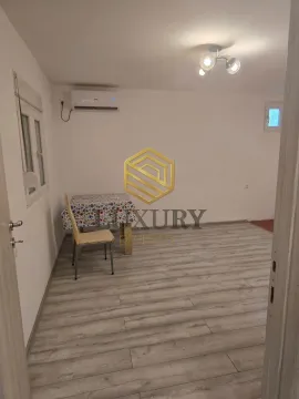 Small bright room with laminate flooring, an air conditioner, and a table with a chair. - image 3