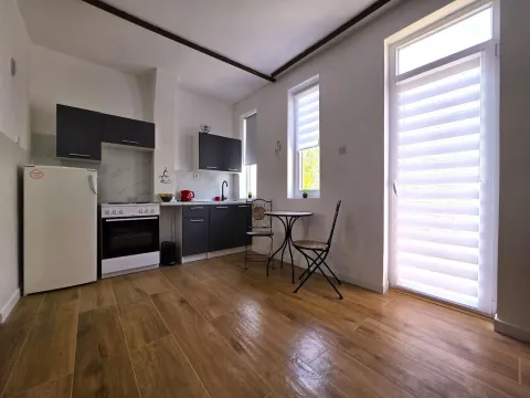 Kitchen equipped with dark cabinetry and white appliances, featuring a small dining table. - image 9