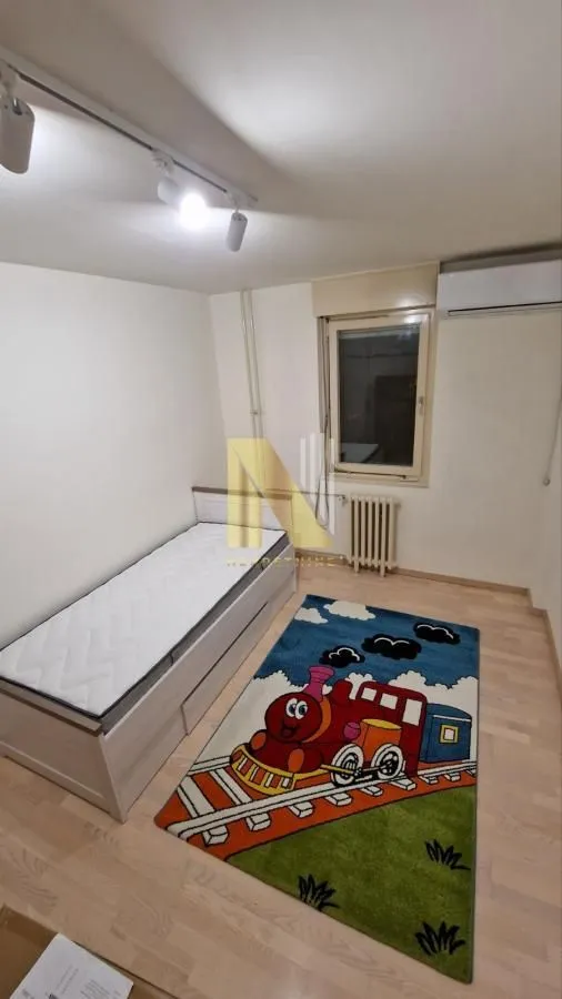 Dečja soba sa krevetom i šarenim tepihom.