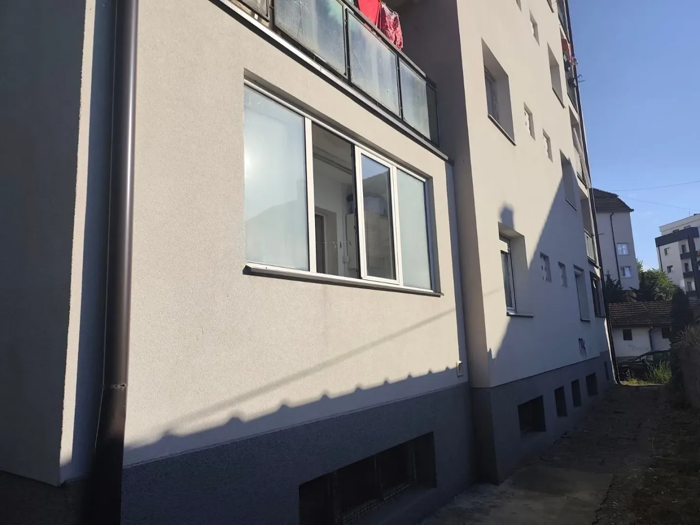 Spoljašnji izgled stambene zgrade sa svetlom fasadom i prozorima.