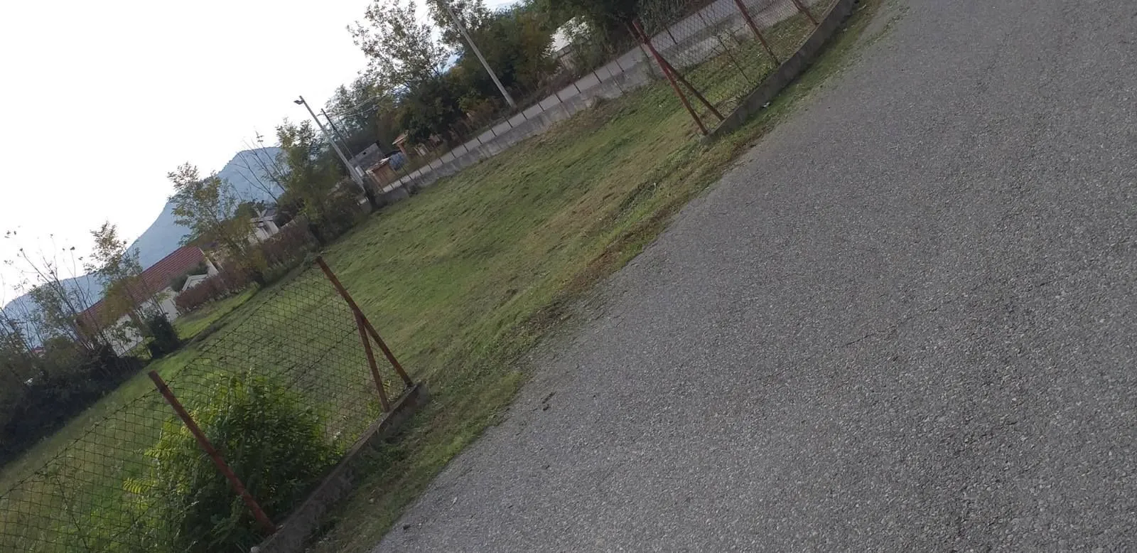 Pogled na ravan travnati plac pored puta.