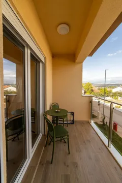 Natkriveni balkon sa garniturom za sjedenje i pogledom na ulicu. - image 9