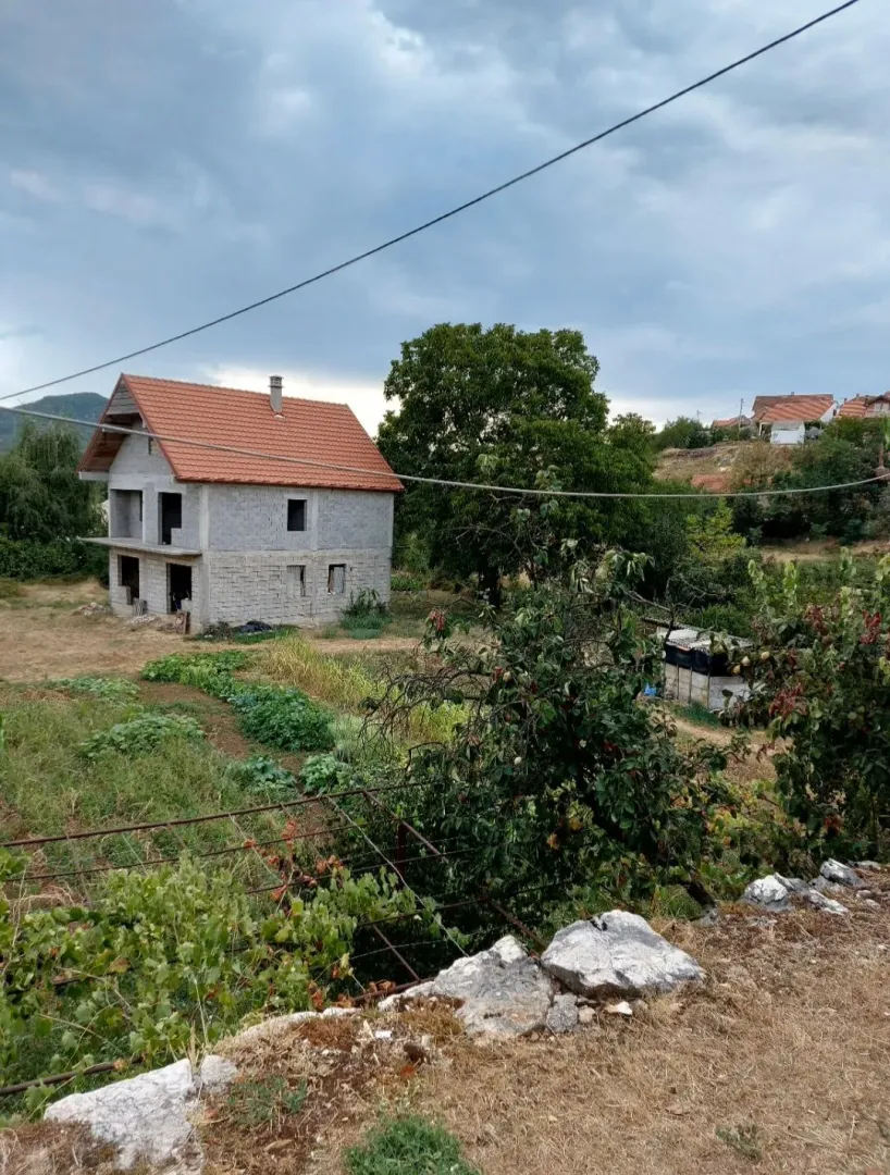 Pogled na kuću u izgradnji sa okućnicom i zelenilom.