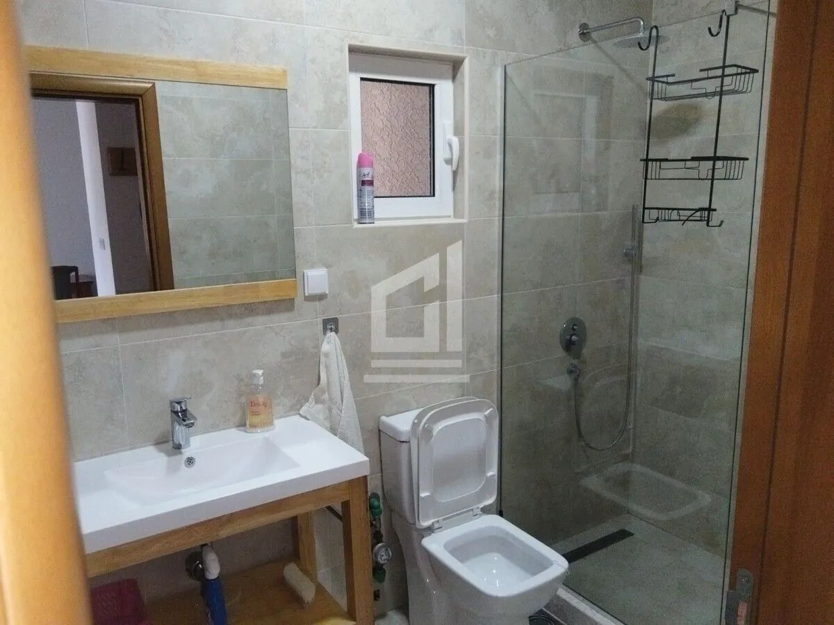 Kupatilo opremljeno umivaonikom, WC šoljom i tuš kabinom.